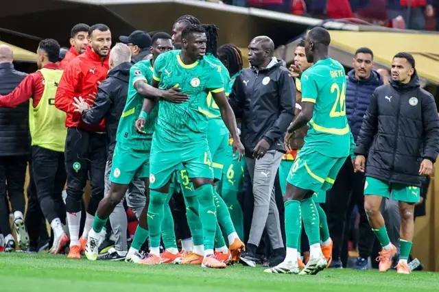 The Sénégal team angrily confronts referee Jean-Jacques Ndala after he awarded a late penalty following a VAR review during the Africa Cup of Nations final against Morocco at the Prince Moulay Abdellah stadium on January 18, 2026, in Rabat, Morocco.