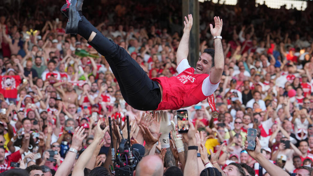 Arsenal manager Mikel Arteta lifts the Premier League trophy as players celebrate their title win after the English Premier League football match between Crystal Palace and Arsenal in London, England, Sunday, May 24, 2026.