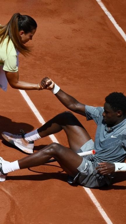 Ana Carvalho, l'arbitre de chaise, aide Moïse Kouame à se relever, lors du match du 2e tour de Roland-Garros, le 28 mai 2026. (MILLEREAU PHILIPPE / AFP)