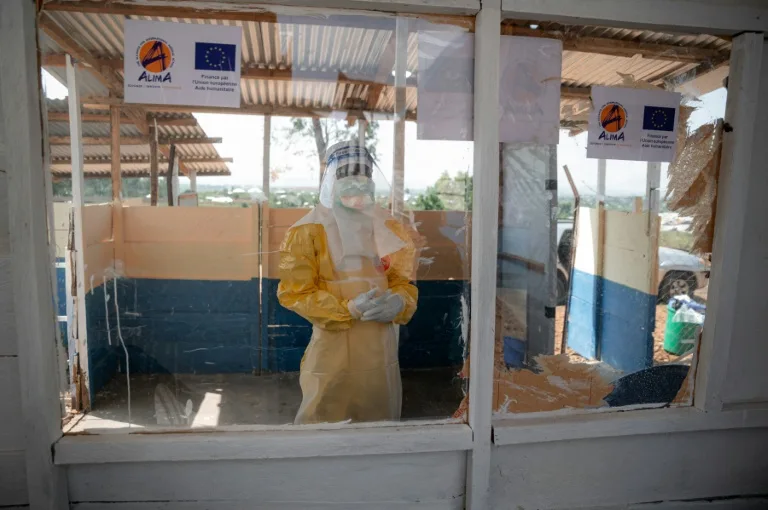 Health workers in protective gear assisting a patient during an Ebola outbreak