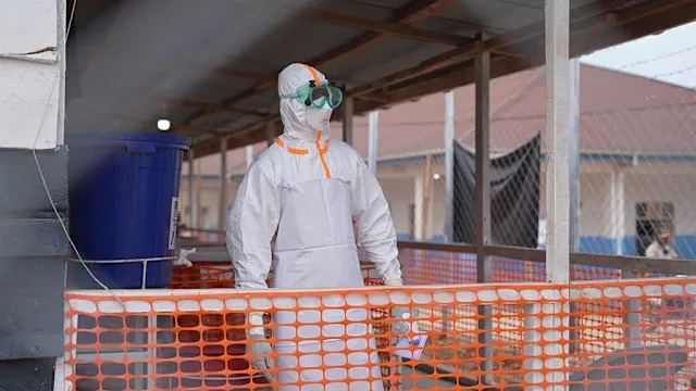 Health workers in protective gear attending to patients in a treatment center